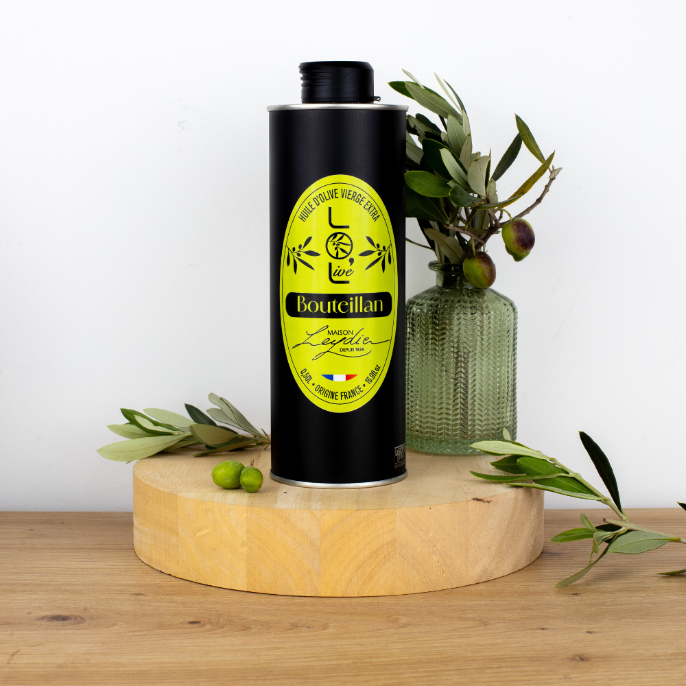 Bouteille d'huile d'olive vierge extra Bouteillan de Maison Leydier, sur fond naturel avec olives fraîches et branches d'olivier. Produit artisanal de qualité, fabriqué en France.
