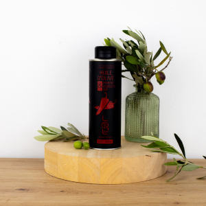 Bouteille d'huile d'olive au piment d'Espelette de Maison Leydier, aromatisée, sur fond naturel avec olives fraîches et branches d'olivier. Produit culinaire de qualité, fabriqué en France.