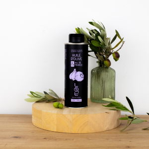 Bouteille d'huile d'olive à l'ail de France de Maison Leydier, aromatisée, sur fond naturel avec olives fraîches et branches d'olivier. Produit culinaire de qualité, fabriqué en France.