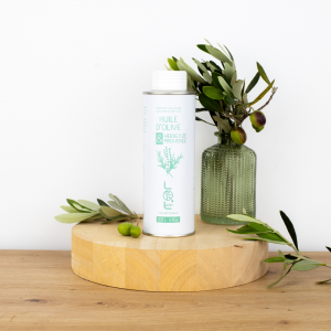Bouteille d'huile d'olive aux herbes de Provence de Maison Leydier, aromatisée, sur fond naturel avec olives fraîches et branches d'olivier. Produit culinaire de qualité, fabriqué en France.